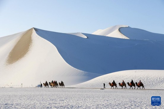 游客在鸣沙山月牙泉景区欣赏雪景。新华社发（张晓亮摄）