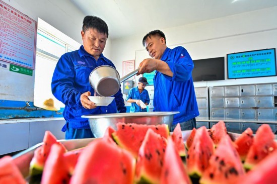 在天津长芦海晶集团有限公司的盐田作业现场，工人在休息区领取绿豆汤纳凉解暑。新华社发（杜鹏辉 摄）