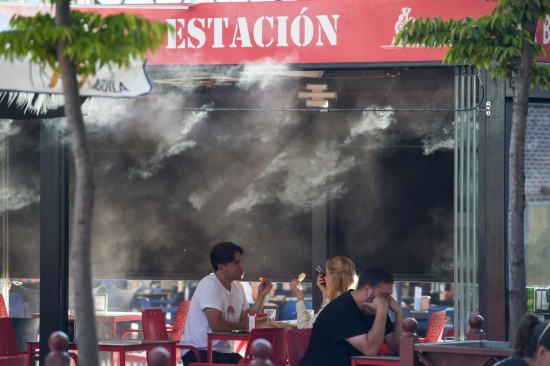 2025年9月17日，在西班牙马德里，顾客在水雾装置附近用餐。新华社发（古斯塔沃·巴连特摄）