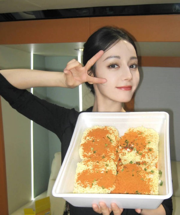 迪丽热巴举着泡面拍照，心情愉悦。