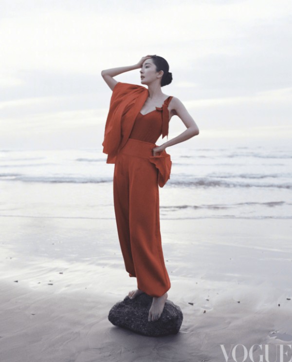 杨幂身着红装立于海边,抬手轻抵脖颈的姿态利落明艳。