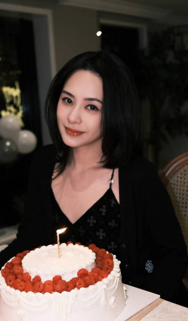 阿娇坐在生日蛋糕前拍照。