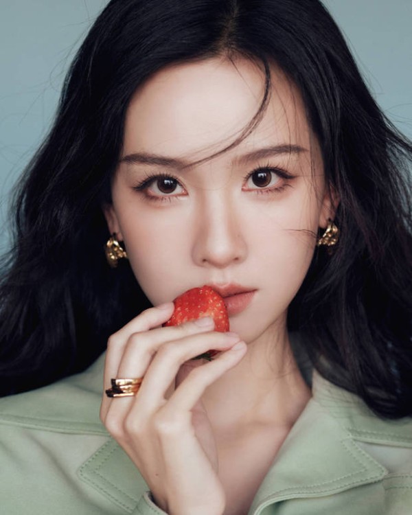 陈都灵手持草莓轻贴唇边,神态灵动。