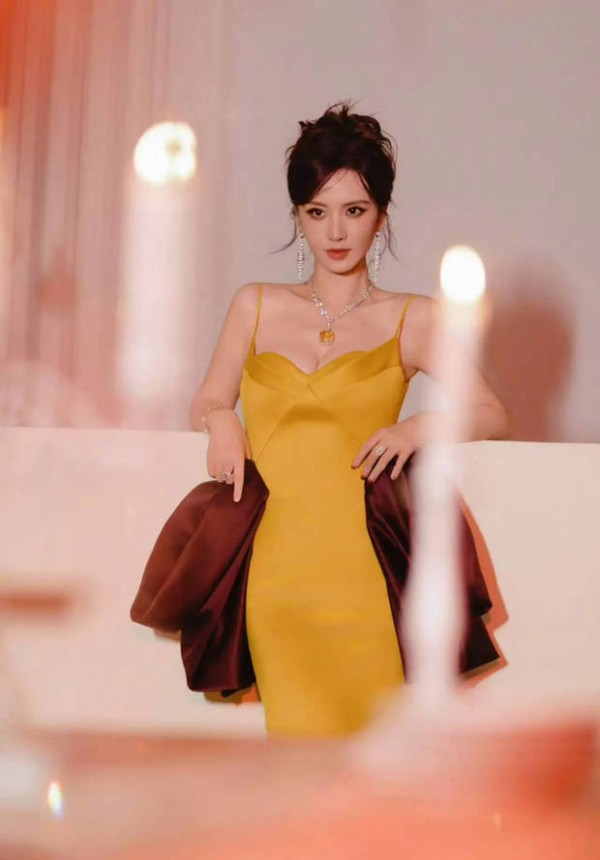 张萌手持珍珠链，发丝轻拂气质冷艳。