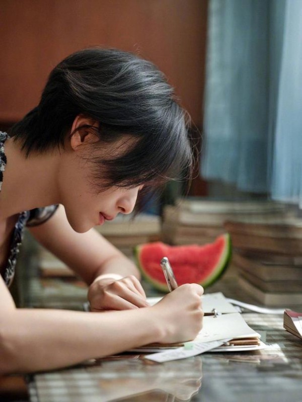 倪妮低头写字，格纹裙尽显文艺感。