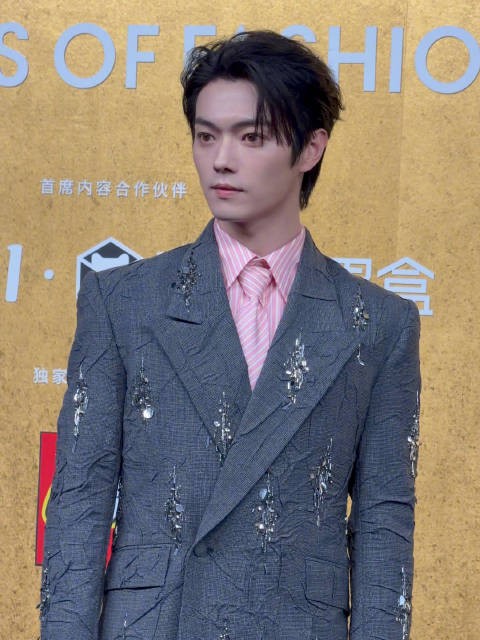 许凯身着褶皱处理西装，搭配粉色条纹衬衫及领带亮相